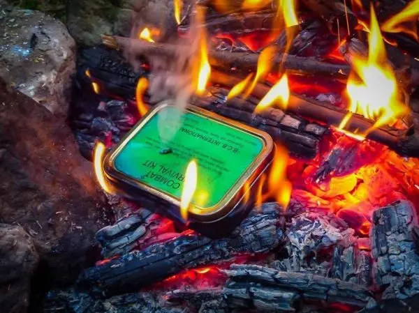 Kleine Flamme umgibt eine Dose im Glutbett eines Feuers