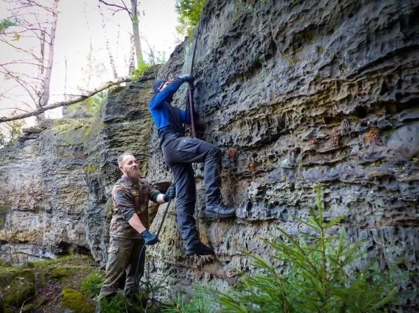 Kletterer nutzt Seil zur Unterstützung beim Aufstieg an einer Felswand
