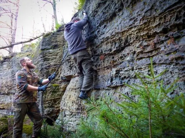 Kletterer nutzt Seil zur Unterstützung beim Aufstieg an einer Felswand