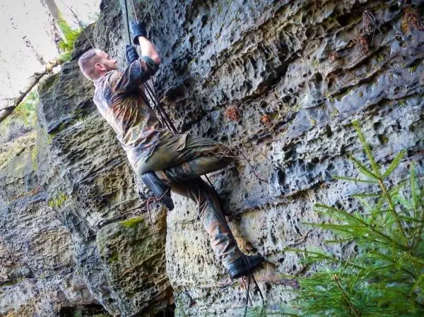 Klettert an einer Felswand mit einem Seil