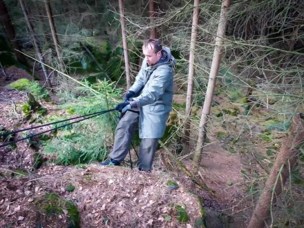 Mann zieht an einem Seil in einem bewaldeten Gebiet