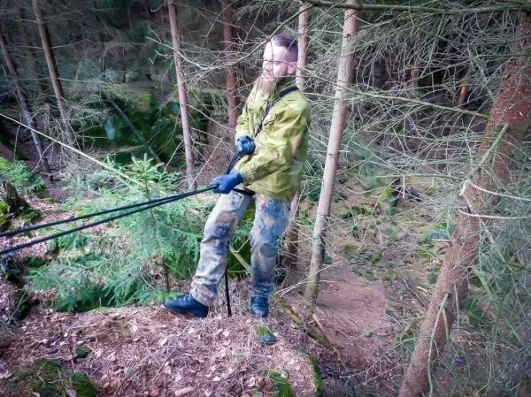 Mann zieht an einem Seil über einen Abhang im Wald