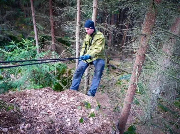 Mann zieht an einem Seil über einen Abhang im Wald