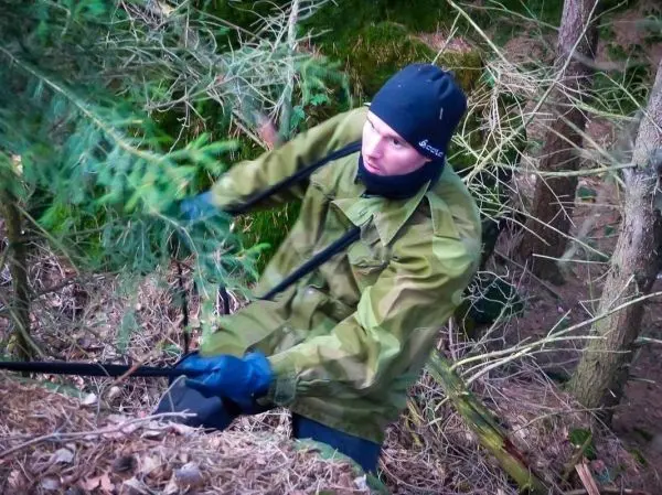 Mann zieht an einem Seil zwischen Bäumen in bewaldeter Umgebung