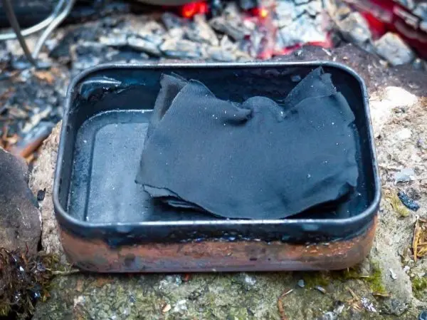 Metallbehälter mit schwarzem Material darin auf einem Stein