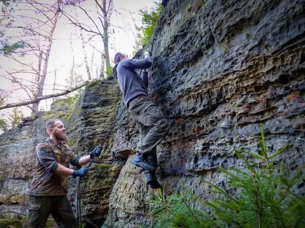 Person klettert an einer Felswand hoch, andere Person sichert sie