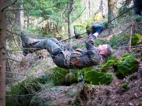 Person schwingt an einem Seil zwischen Bäumen