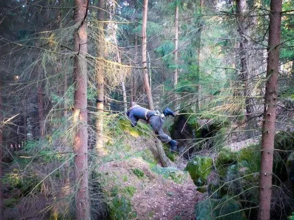 Person überquert unebenes Gelände zwischen Bäumen und Felsen