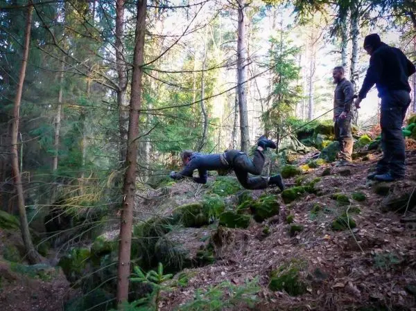 Selbstgebaute Seilquerung wird von einer Person überquert, während andere sichern