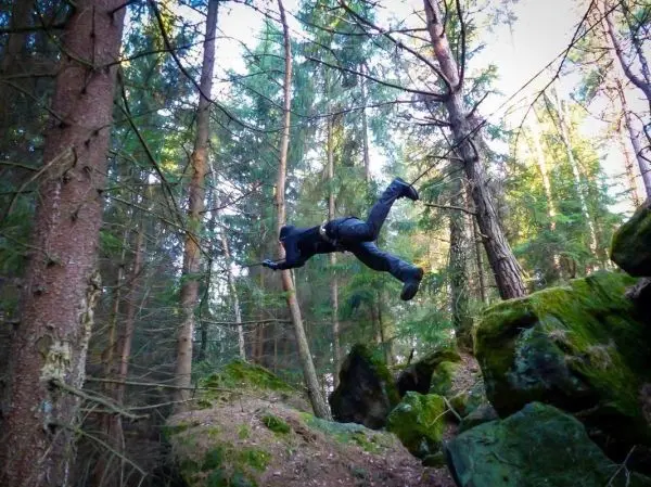 Sprung über einen Felsen im Wald zwischen Bäumen