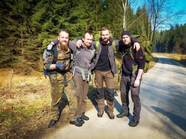 Vier Personen mit Rucksäcken stehen auf einem Waldweg