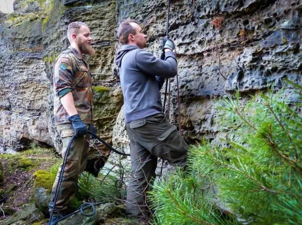 Zwei Personen befestigen Seile an einer Felswand zur Sicherung