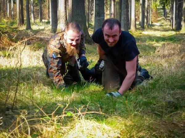 Zwei Personen kriechen durch hohes Gras im Wald