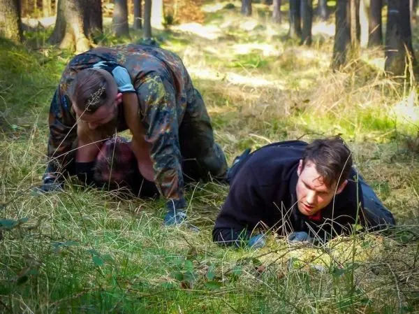 Zwei Personen kriechen durch hohes Gras im Wald