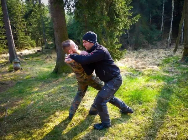 Zwei Personen üben eine Kampftechnik im Wald