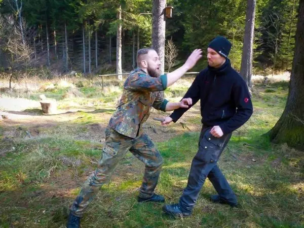 Zwei Personen üben eine Selbstverteidigungstechnik im Wald