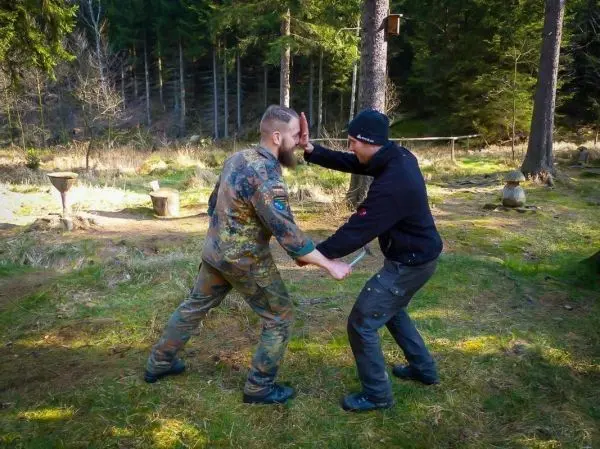Zwei Personen üben eine Selbstverteidigungstechnik im Wald