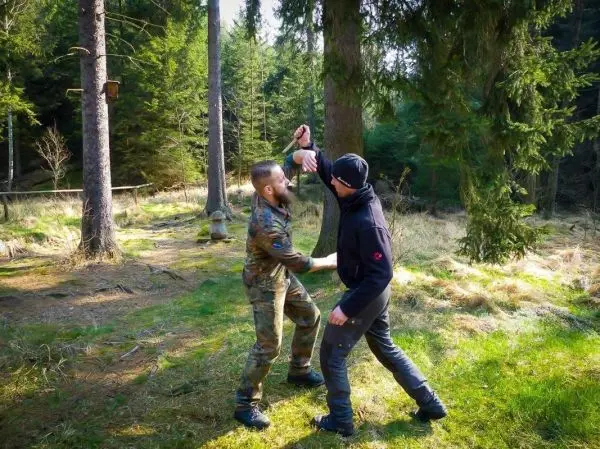 Zwei Personen üben eine Selbstverteidigungstechnik im Wald