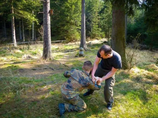 Zwei Personen üben eine Technik zur Kontrolle im Wald auf dem Boden