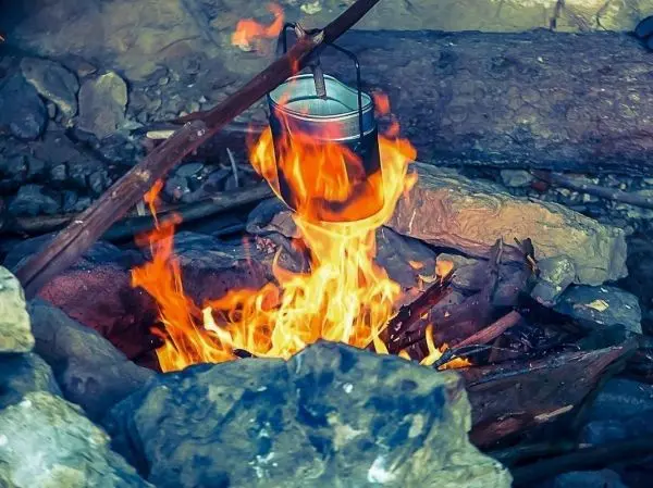 Eimer hängt über einem Feuer in einer Steinumrandung