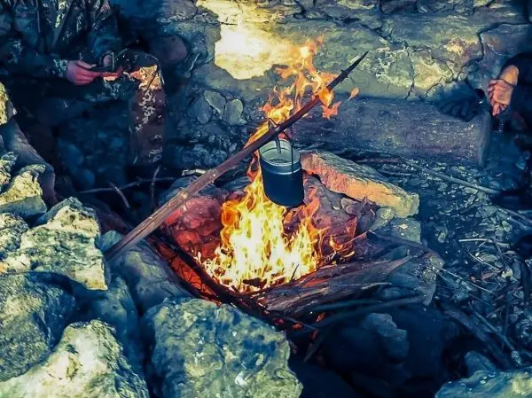 Ein Topf hängt über einem Feuer in einer Steinschale