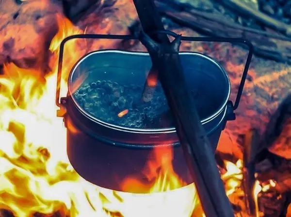 Ein Topf hängt über einem Feuer und kocht Wasser