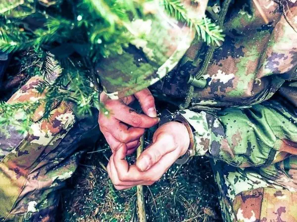 Hände binden einen improvisierten Knoten aus Naturmaterialien