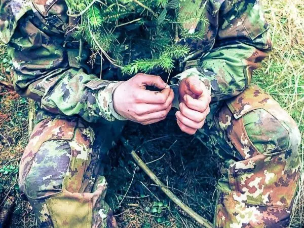 Hände knoten Zweige zusammen, um eine improvisierte Konstruktion zu erstellen