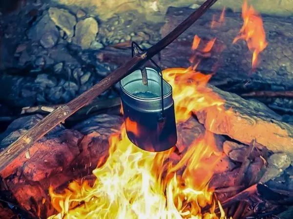 Kessel hängt über einem offenen Feuer auf einem Holzstock