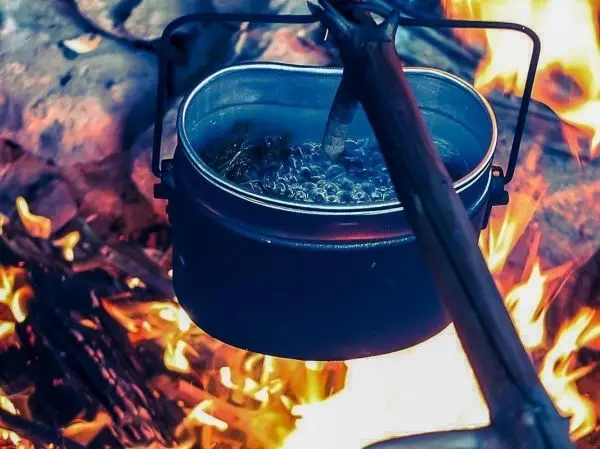 Kessel hängt über offenem Feuer und kocht Wasser