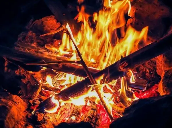 Kleine Flamme mit brennenden Holzstücken und glühenden Kohlen