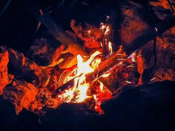 Kleine Flamme zwischen Steinen mit glühenden Kohlen und Funken