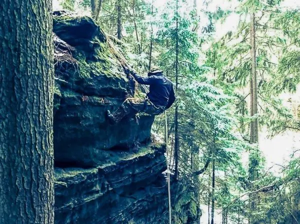 Kletterer nutzt Felsen zur Fortbewegung in bewaldeter Umgebung