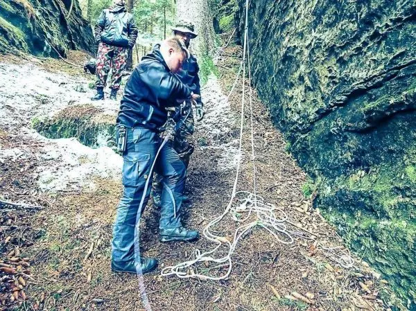 Mann knotet Seil für eine Seilquerung zwischen Felsen im Wald