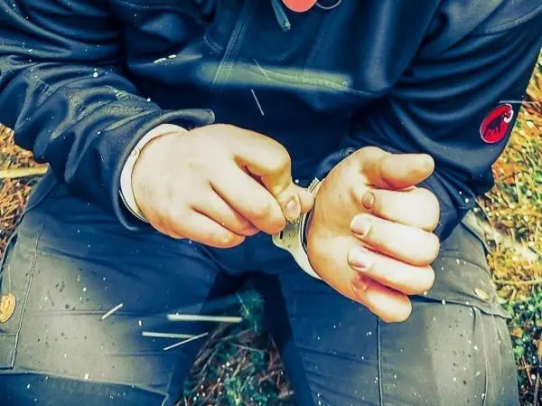 Person befestigt ein Armband am Handgelenk beim Überlebenstraining