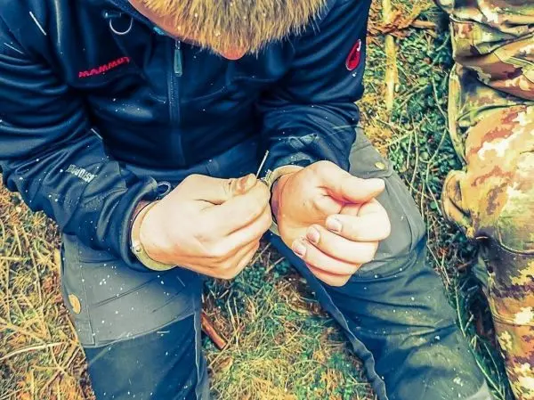 Person befestigt eine Schnur an einem Handgelenk beim Überlebenstraining