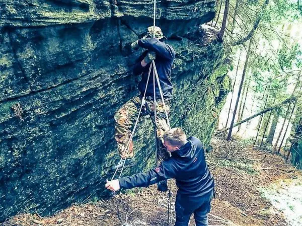 Person klettert an einer Felswand mit Seilunterstützung beim Überlebenstraining