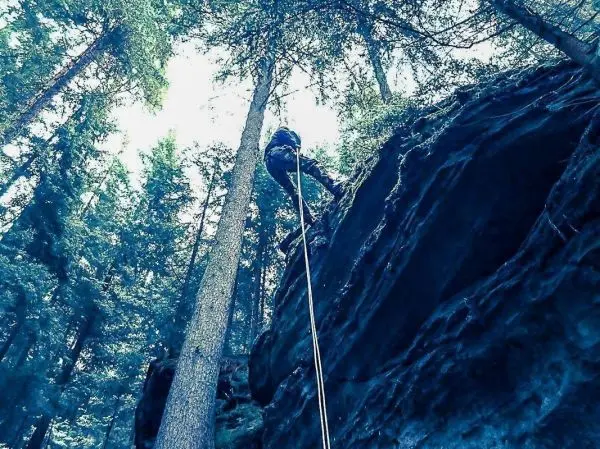 Person seilt an einer Felswand im Wald ab