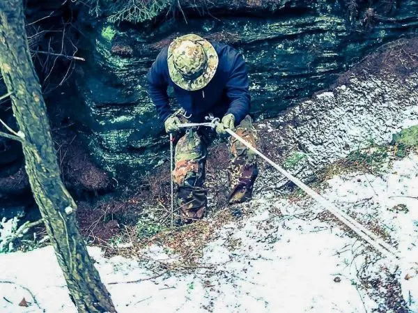 Person sichert sich mit Seil an einem steilen Hang