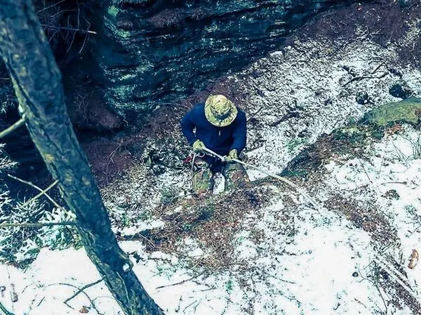 Person sichert sich mit Seil an einer steilen, schneebedeckten Abbruchkante