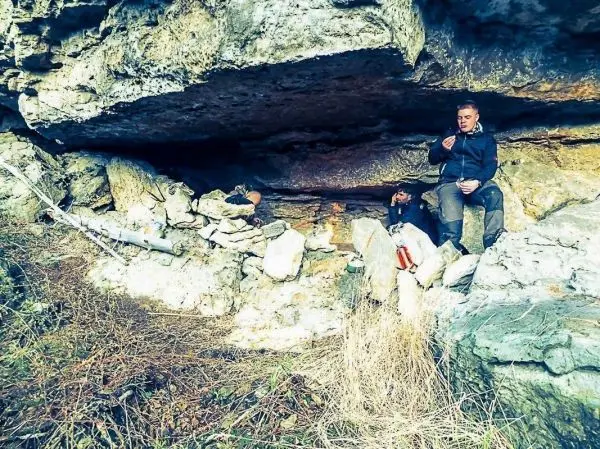 Person sitzt in einer natürlichen Höhle und isst etwas