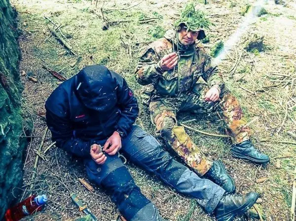 Zwei Personen sitzen im Wald, eine hält etwas in der Hand