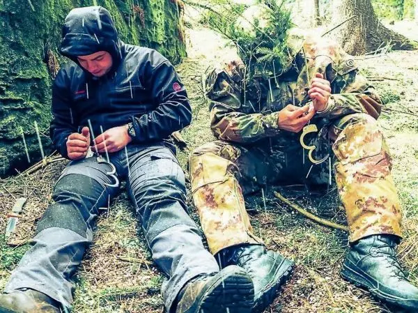 Zwei Personen sitzen im Wald und knoten Seile zusammen