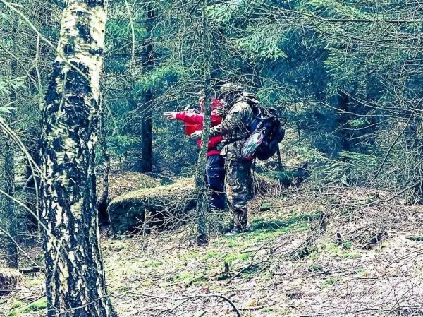 Zwei Personen stehen im Wald, eine zeigt in eine Richtung