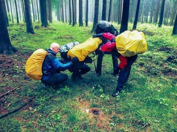 Gruppierung von Personen mit Rucksäcken bei einer Seilquerung im Wald