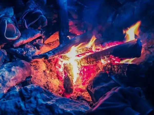 Kleine Flamme brennt auf Holzscheiten zwischen Steinen