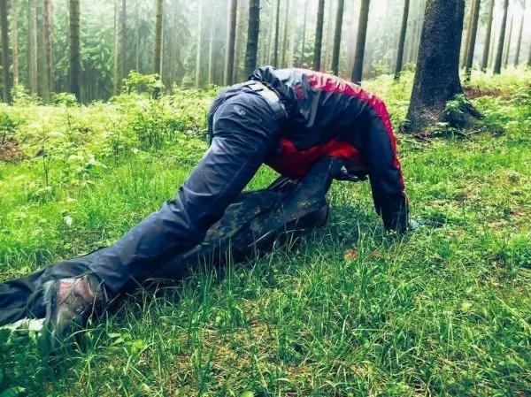 Person führt eine Seilquerung über eine improvisierte Trage im Wald durch