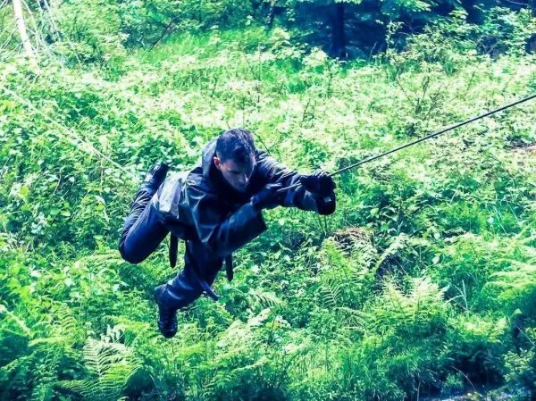 Person hängt an einem Seil und bewegt sich durch das Unterholz