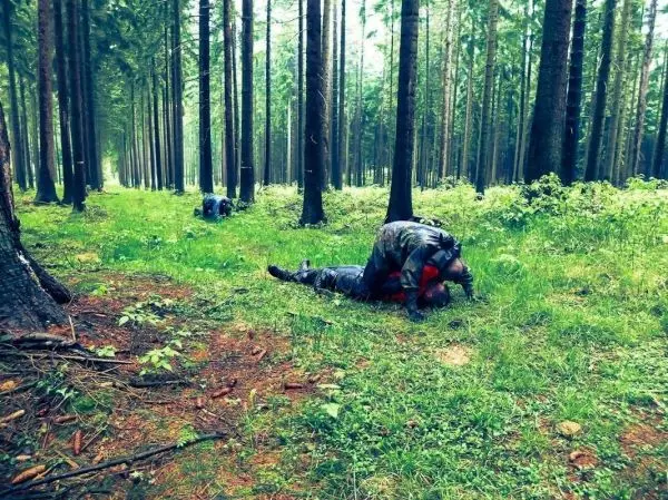 Person liegt auf dem Boden zwischen Bäumen im Wald