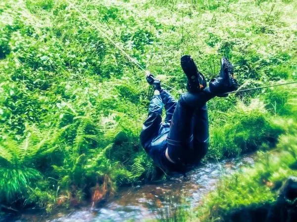 Person schwingt an einem Seil über einen kleinen Bach